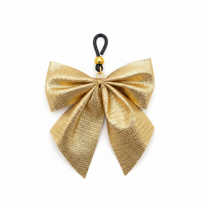 Gouden strik tepelhanger close-up - detail van metallic stof en zwarte clip